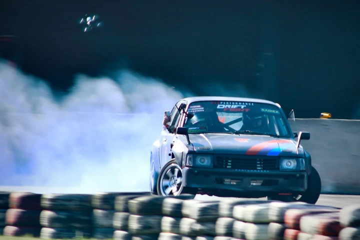 A HeuPerformance car drifting at night, surrounded by tire smoke.